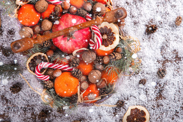 Fototapeta na wymiar Christmas New Year Composition with Tangerines Pine cones Walnuts,Hazelnuts and Candy Cane on wooden Vintage Tray.Holiday Card.Holiday Decoration to Russian Tradition.Drawn Snowfall.selective focus .