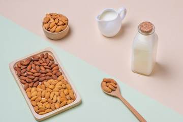 Fototapeta na wymiar Almonds and milk bottle on light background. Almond nuts in spoon.