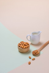 Almonds and milk bottle on light background. Almond nuts in spoon.