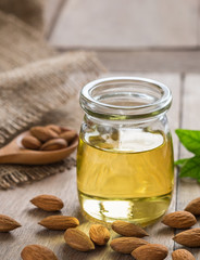 Almond oil in glass bottle and almonds on wooden table