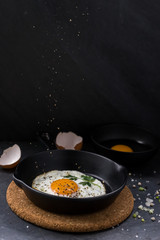 fried egg in black pan and ingredient on dark background