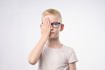 Fototapeta premium Caucasian blond child reviewing eyesight closing half of face with hand.