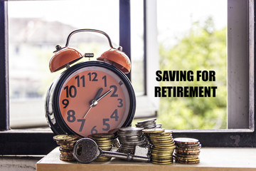 Clock, key, and coin with the word SAVING FOR RETIREMENT - the concept of savings