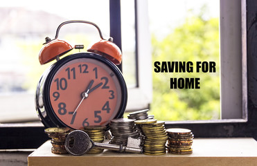 Clock and coin with the word SAVING FOR HOME - the concept of savings