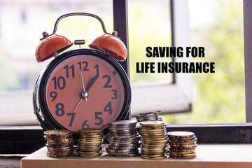 Clock and coin with the word SAVING FOR LIFE INSURANCE - the concept of savings