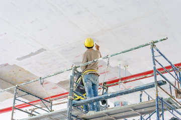 Construction workers on scaffolding tower painting and renovating building floor in construction...