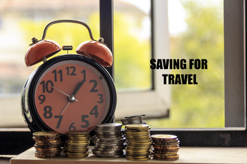 Clock and coin with the word SAVING FOR TRAVEL - the concept of savings