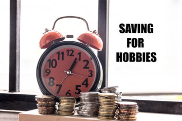 Clock and coin with the words SAVING FOR HOBBIES - the concept of savings