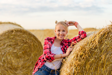 Naklejka na ściany i meble Young girl on straw sheaves in a field