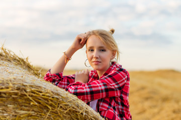 Young girl on straw sheaves in a field