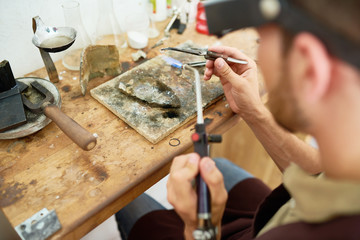 Portrait of young man welding  metal at table in workshop