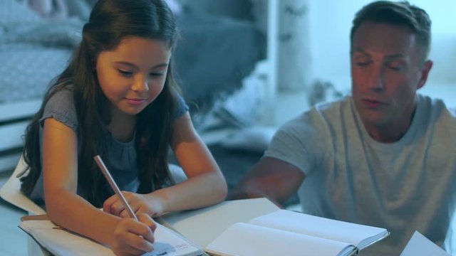 Caring father helping his school daughter to do her home assignment