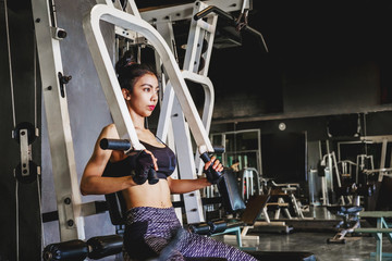Fototapeta na wymiar Asian young fitness woman execute exercise with exercise-machine in gym