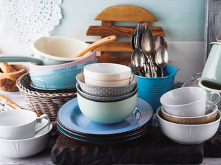 Ceramic and enamel crockery tableware on wooden background. Pastel vintage colors