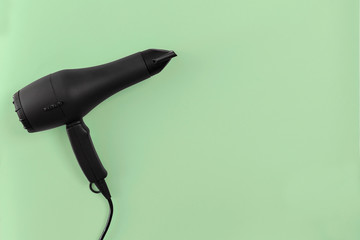 Black hair dryer on green paper background