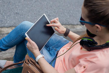 Young girl is sitting on the bench and watching tablet