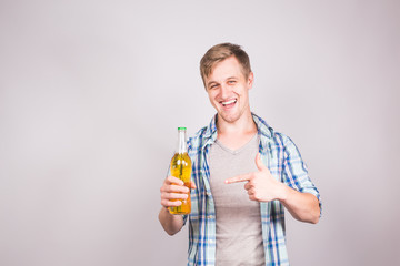 A handsome young man feeling happy showing thumbs up and holding a bottle of beer.