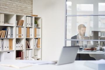 Background image of modern office space with blurred businessman working behind glass wall, copy space