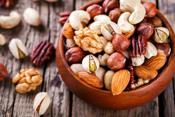 Nuts Mixed in a wooden plate.Assortment, Walnuts,Pecan,Almonds,Hazelnuts,Cashews,Pistachios.Concept of Healthy Eating.Vegetarian.selective focus.