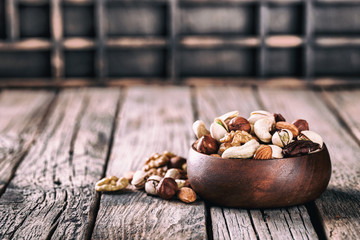 Nuts Mixed in a wooden plate.Assortment, Walnuts,Pecan,Almonds,Hazelnuts,Cashews,Pistachios.Concept of Healthy Eating.Vegetarian.Copy space.Toned image.Vintage style.selective focus.