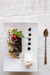 Chocolate pie on white square cut plate with decoration from cherry, almond and mint. Delicious dessert serving in restaurant with ice-cream ball, top view with free space above