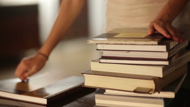 Woman puts stack of books on the table