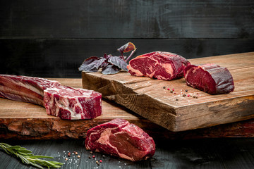 Fresh raw beef on cutting board with fresh basil and a sprig of rosemary