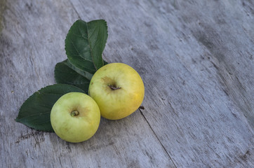 two large yellow apples lie on an old wooden table outdoors
