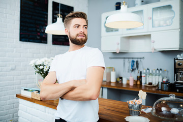 confident cafe owner looking away with arms crossed while standing in front of counter