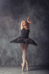 Young beautiful woman prima theater in a black festive pack, white pantyhose, white pointe shoes beautifully dancing russian ballet in a black dance studio © Виталий Сова