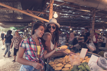 Young Women Talking While Buy Exotic Fruits On Tropical Market Happy Smiling Girld Tourists Choosing Products In Asian Traditional Bazaar