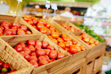 Ripe tomatoes in wooden boxes in modern supermarket