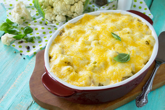 Vegetable casserole cauliflower meat and cheese on a wooden kitchen table, home kitchen.