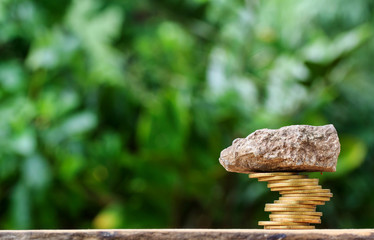 Risky coin stack and stone on top.Financial crisis concept.