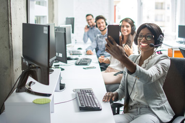 Group of business people taking a selfie while sitting in row and working in call center.