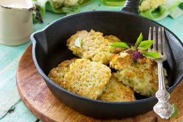 Vegetable pancakes. Fried vegetarian cutlets or fritters on a kitchen wooden table. The concept of...
