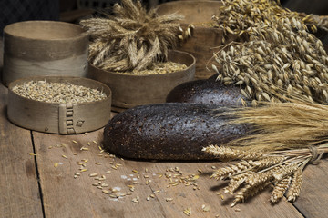 Bread background. Brown whole grain loaves composition on rustic wood with wheat ears scattered around