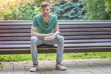 Fototapeta premium Young man reading book in the park
