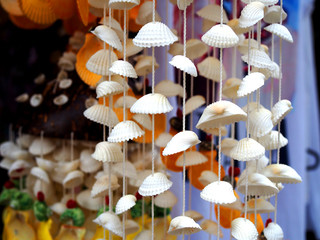 Large hanging white seashell chime in street stall tourist souvenir shop, in sunny weather