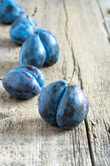 Sweet plums on wooden background Vertical toned