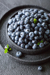 Blueberries on a dark structural background with leaves of green.
