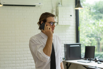 Young businessman talking to the phone while working in office.