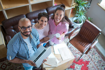 Group of happy young specialists with leader looking at camera