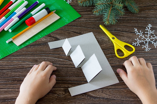 The child adds a birthday card with Christmas presents. Made by own hands. Children's art project, craft for children. Craft for kids.