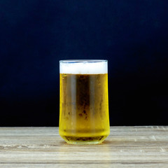 Glass beer on wooden table with black background