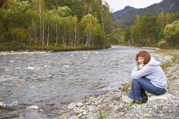 Smiling woman around Altai mountain river. Autumn