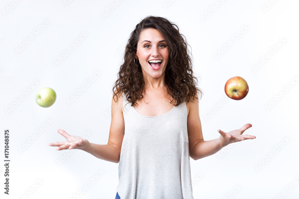 Wall mural Beautiful young woman holding green and red apples over white background.