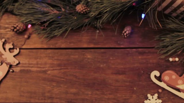 Festive Christmas wooden background. Table with New year decoration and Xmas tree with blurred blinking lights on backdrop loop video. Winter holiday advertising concept