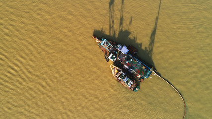 A ship deepening the river by sucking the sand to the shore.