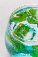 Trendy blue moscato wine in glass, served with mint ice cubes, vertical, closeup